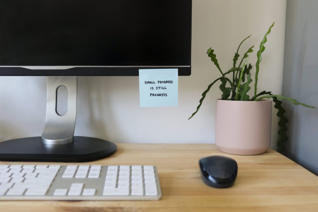 Desktop computer on a desk with a sticky note stuck to it