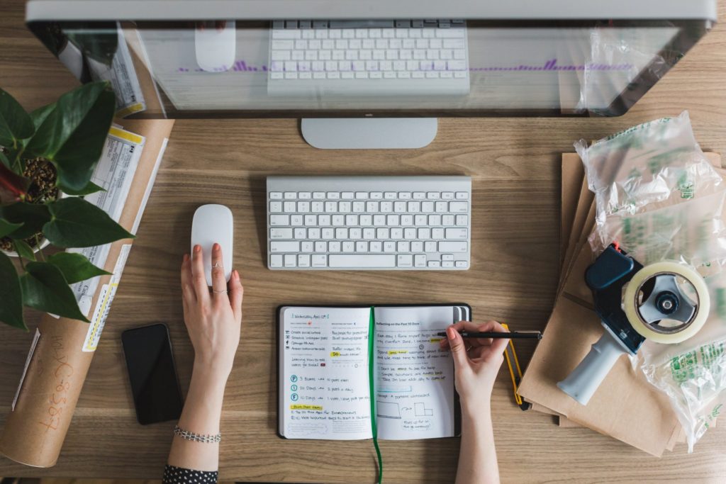 Person working at desk with computer and notebook