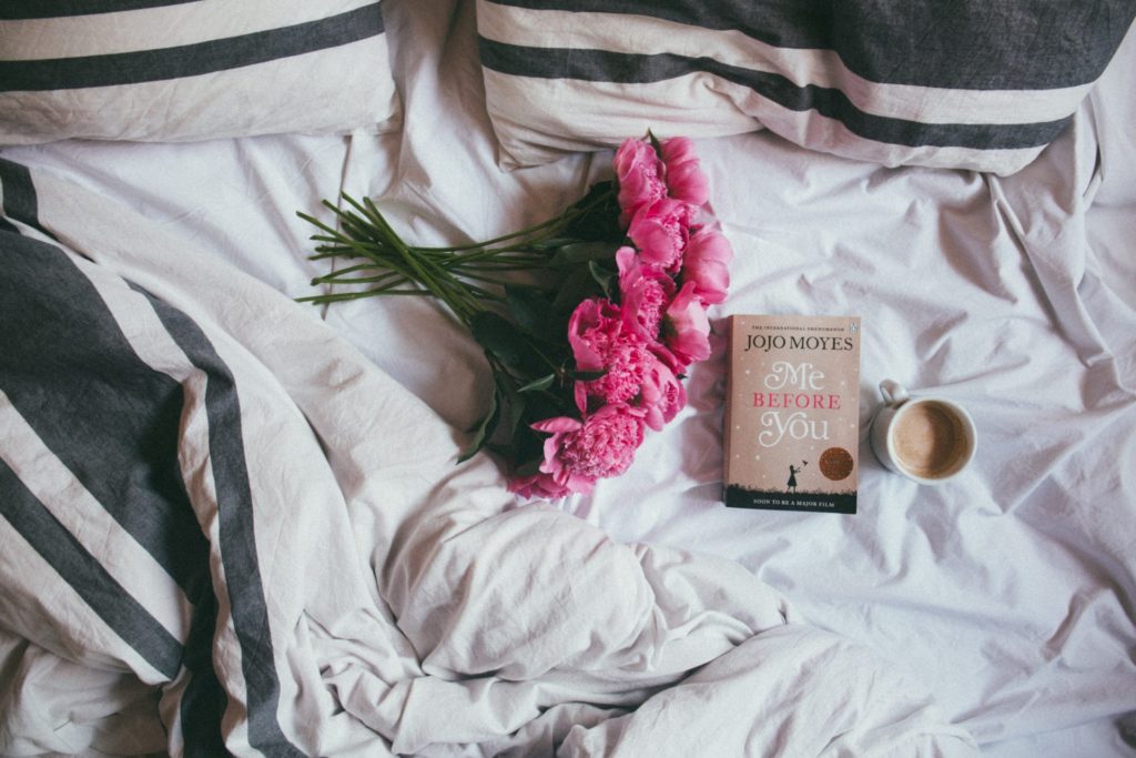 Bed with book, coffee and flowers