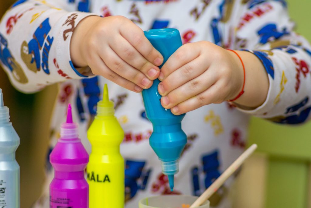 Child squeezing paint bottle