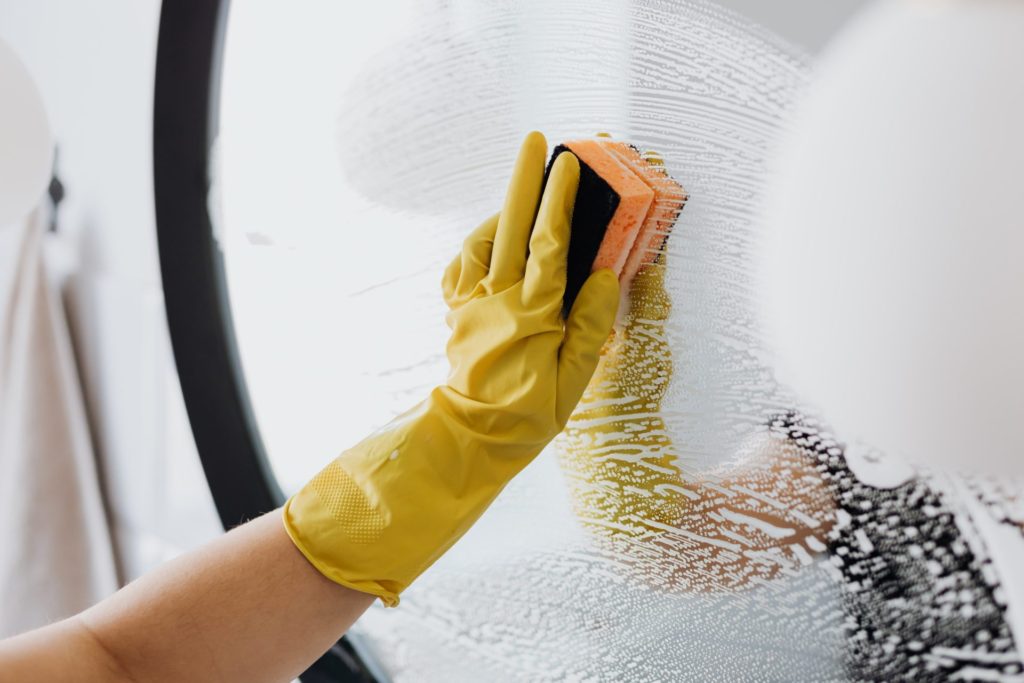 Gloved hand cleaning a mirror